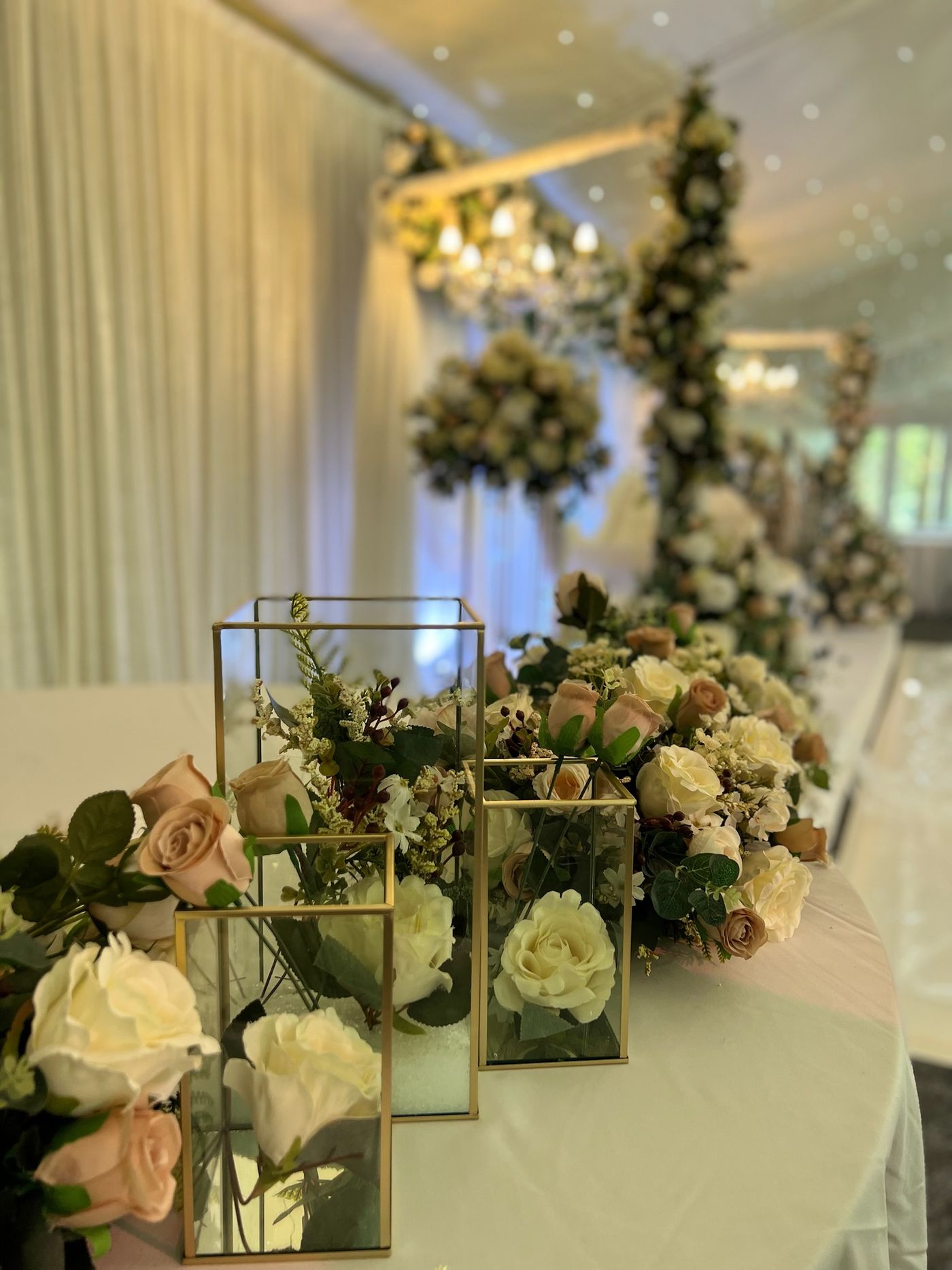 A dressed table with white roses, mirrored boxes and gold lanterns