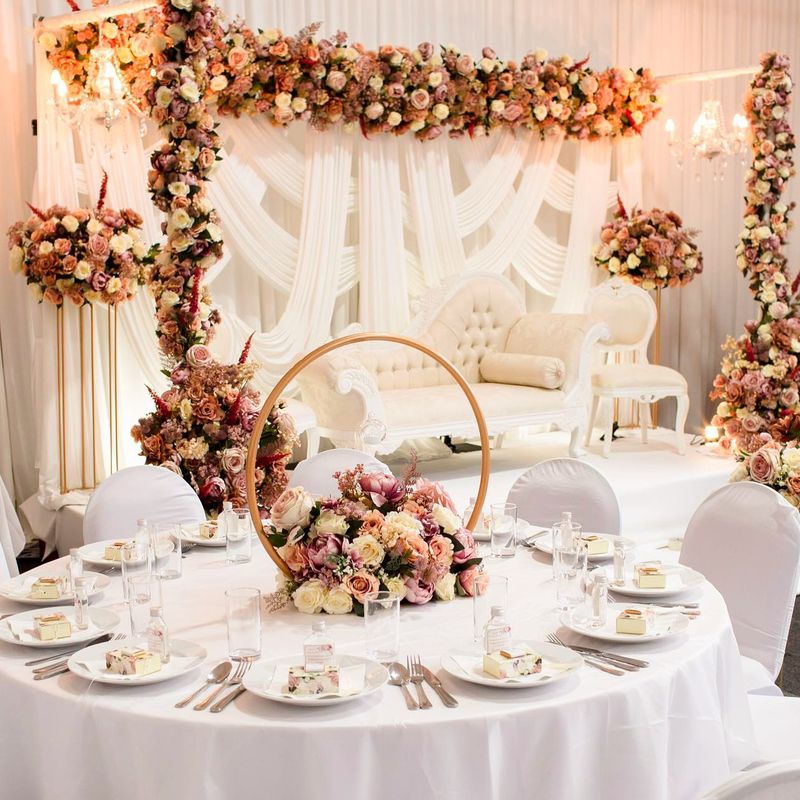 A round table beneath a gold hoop backdrop with white drapes behind