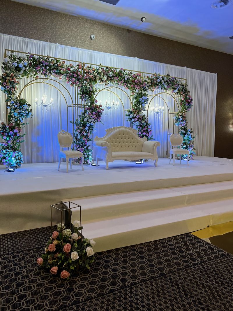 A raised stage framed with a floral arch and set with a sofa