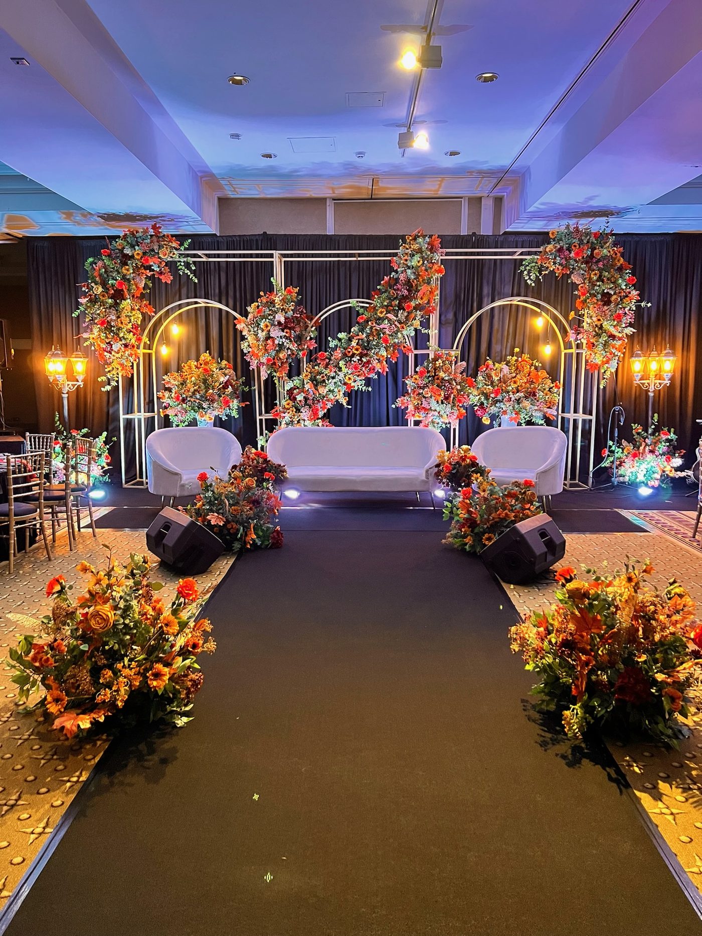 Floral arches and gold candelabra framing a ceremony stage