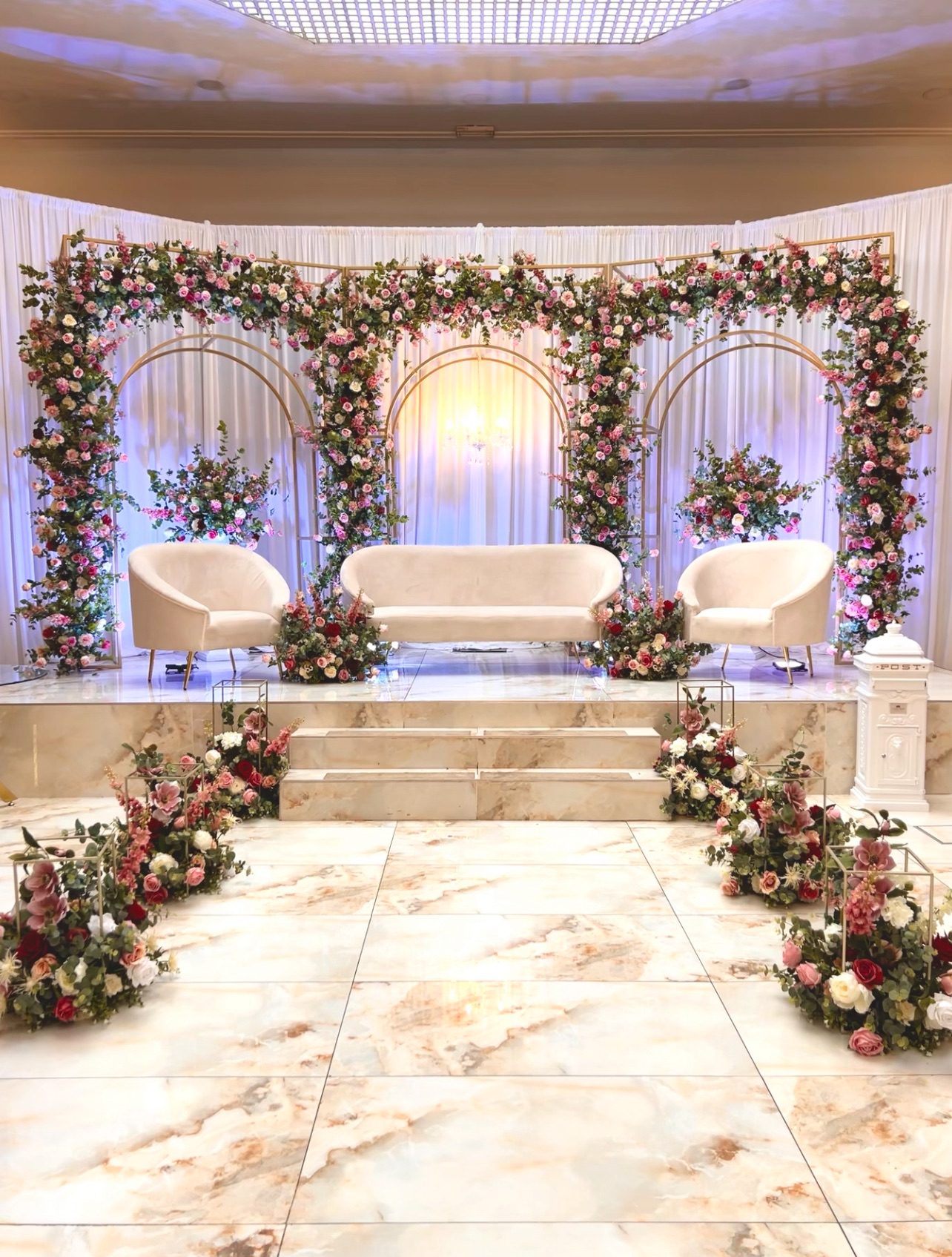 An all-white backdrops setting with floral arches over a marble floor