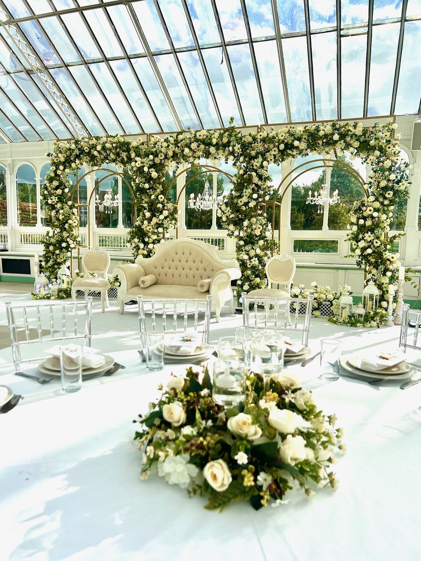 A glass-roofed venue styled with long tables and greenery
