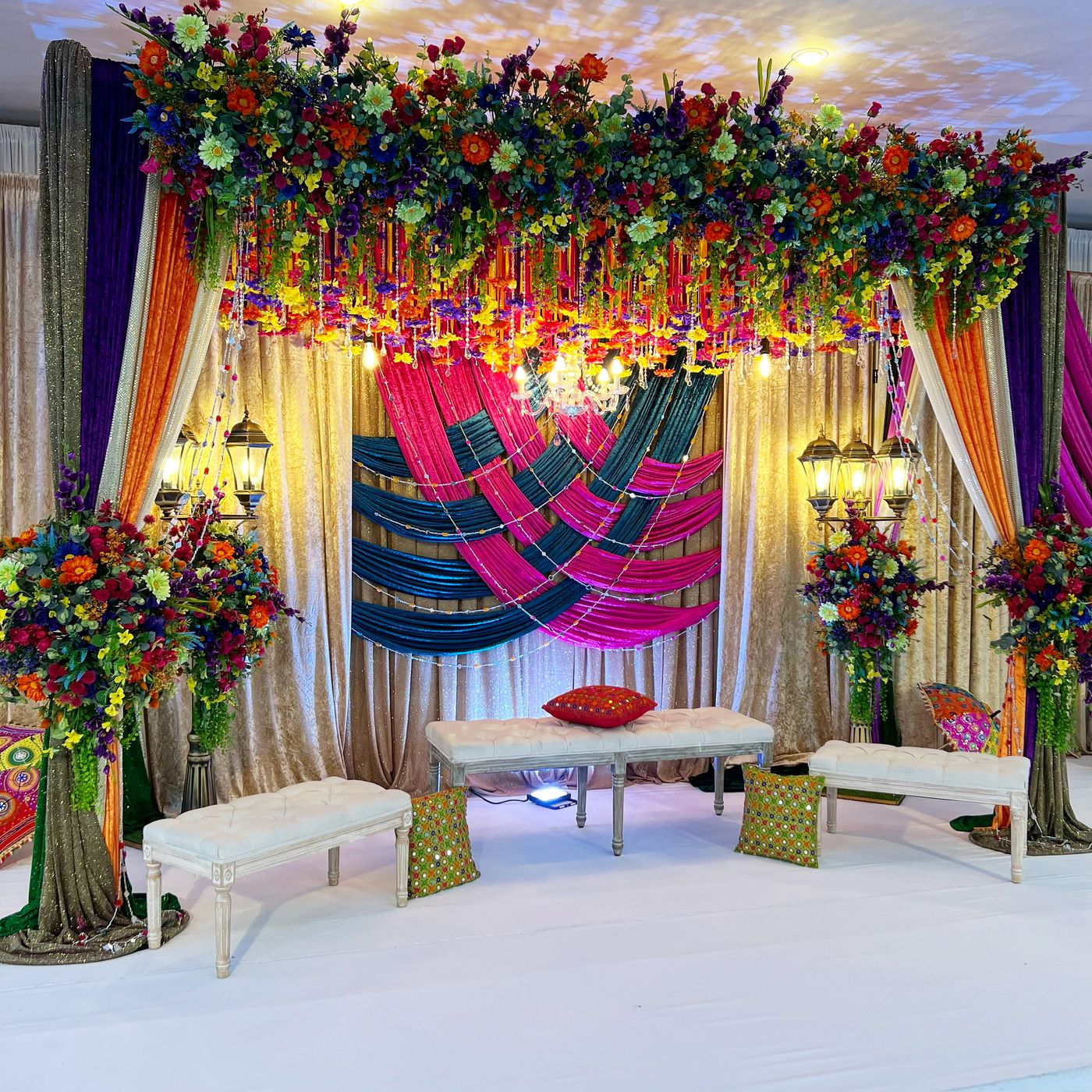 A floral chandelier above a draped swing and a patterned floor