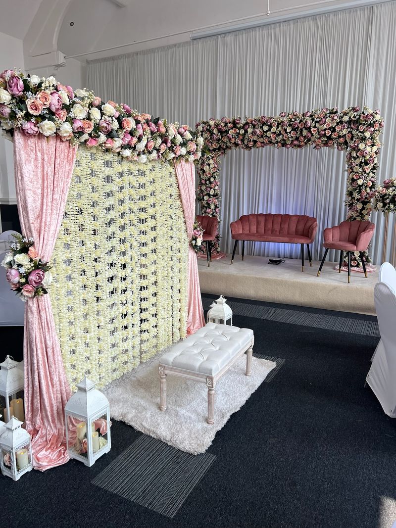 Ivory drapes with a floral arch over a low seat
