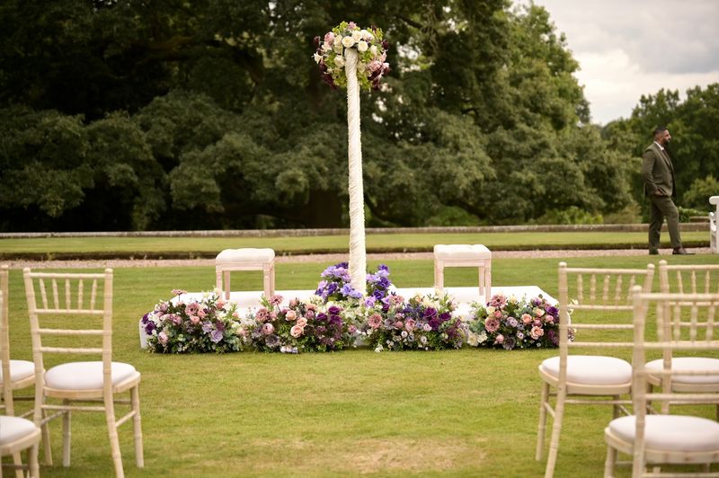 A floral pedestal with white seating on open lawn