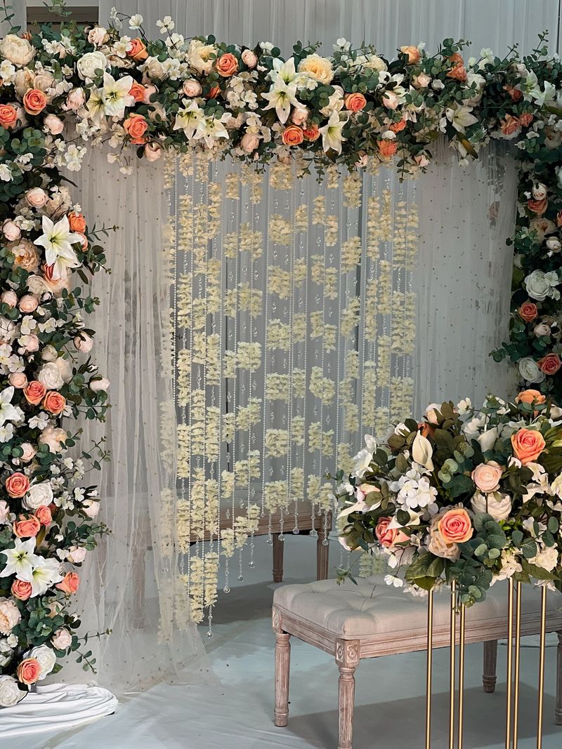 A pale floral arch with white drapes and a low seat
