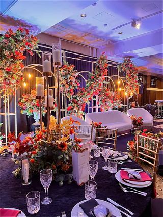 A hall set with floral arches and dressed tables under evening lighting