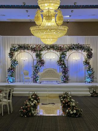 A chandelier above a white and blue floral stage in a grand hall