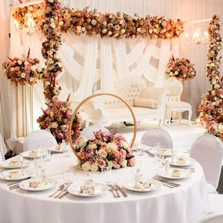 A round table beneath a gold hoop backdrop with white drapes behind