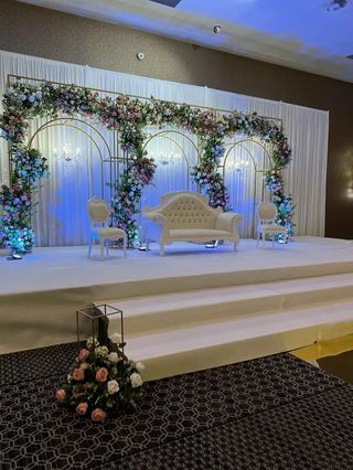 A raised stage framed with a floral arch and set with a sofa