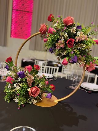 A gold hoop centrepiece dressed with pink and red florals