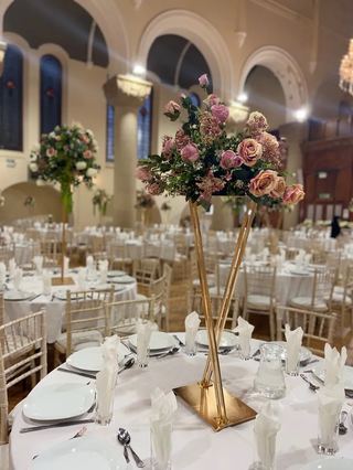 Gold trumpet vases with pink florals in an arched room