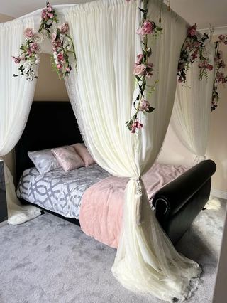 A bedroom dressed with a draped canopy and pink florals