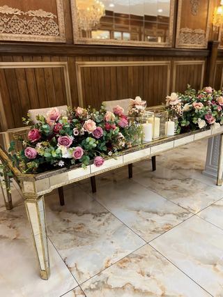 A top table dressed with pink rose garlands