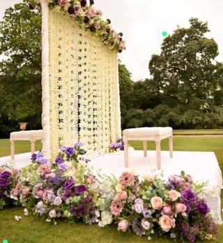 A floral arch panel with a dressed table on a lawn