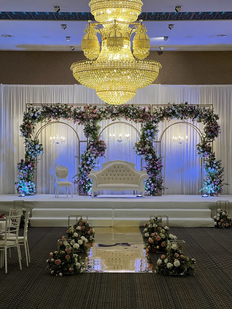 A chandelier above a white and blue floral stage in a grand hall