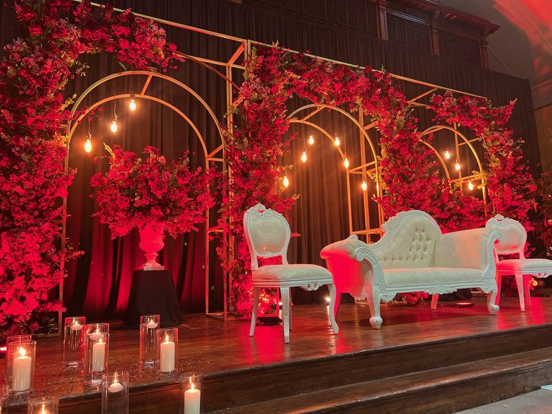 Warm red lighting across gold arches and a cream sofa