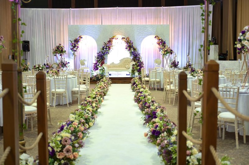 A floral-lined aisle beneath white drapes