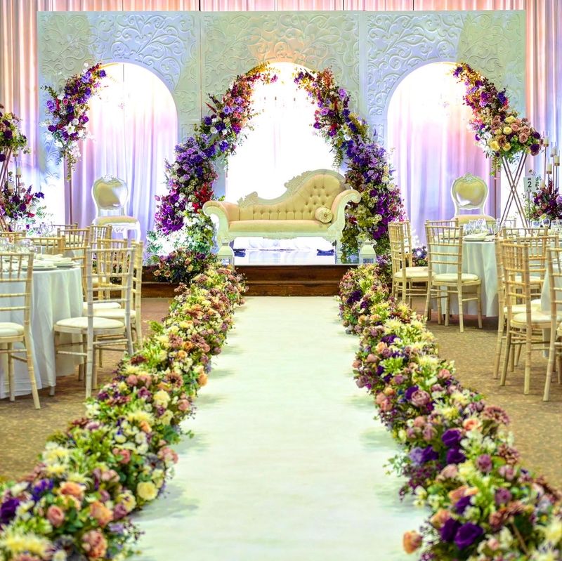 An aisle lined with floral runners leading to a floral arch