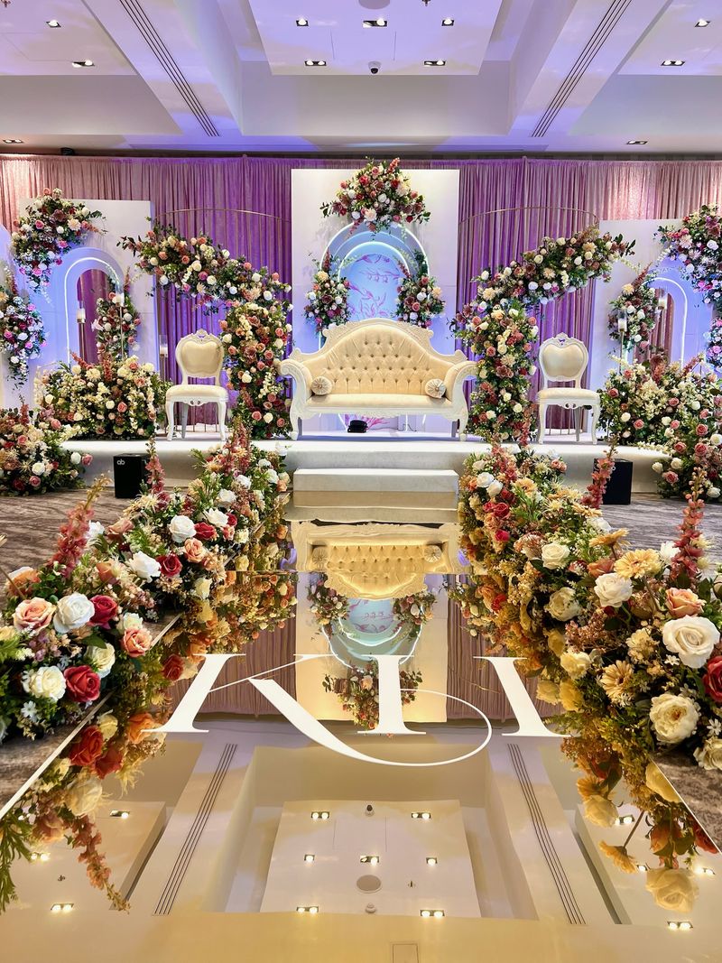 A monogrammed floor decal at the end of a floral-lined aisle